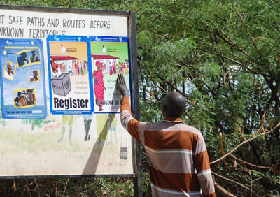 In Kakuma refugee camp, home to an estimated 20,000 southerners, a man looks at a poster promoting the registration period. (Enough-Laura Heaton)