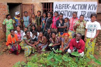 Women pose with Amani in front of the sewing workshop - Action Kivu