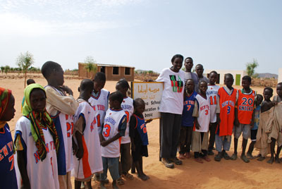 Sister Schools coordinator Stella Kenyi poses with proud owners of New York Knicks jerseys in Djabal camp in eastern Chad. Enough/Omer Ismail